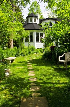 Path of steeping stones leading to a house in lush green garden