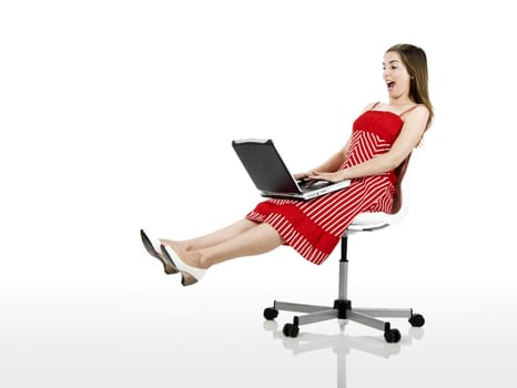 Portrait of a happy woman seated on a chair with a laptop - isolated on white