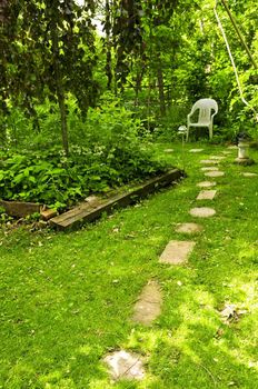 Path of stepping stones leading to secluded corner in lush green garden