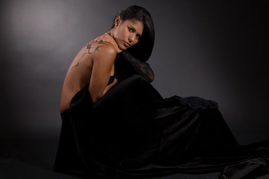 Beautiful brazilian woman wrapped in black velvet on black background