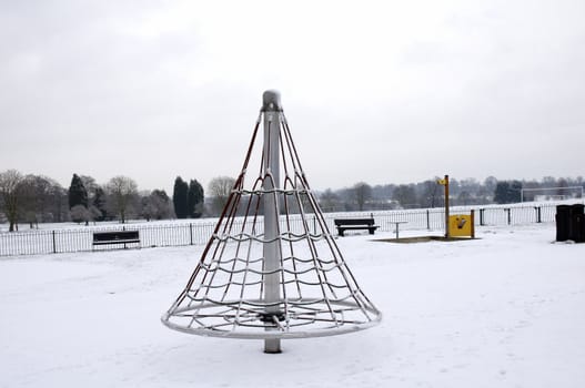 A childrens playground in a park covered in snow