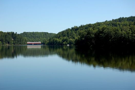 A calm river with a covered bridge in the distance