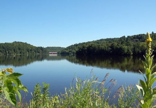 A calm river with a covered bridge in the distance