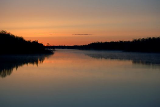 A colorful sunrise over a foggy Northern River