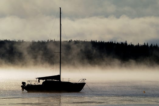 Silhouette of a sailboat in the morning mist