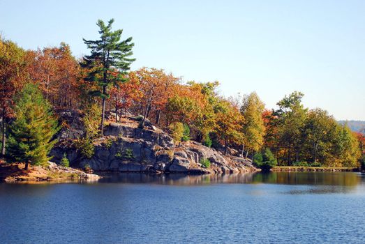 Picture of a calm lake with colorful trees in the background