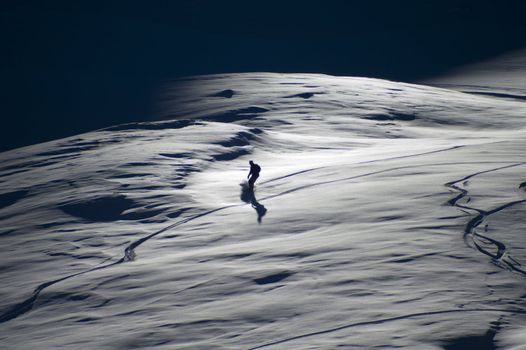 Late afternoon snowboarder on powder