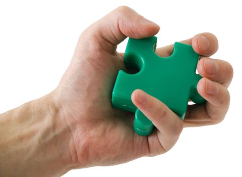 Hand holding a slice of a puzzle of green colour on a white background