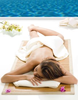 portrait of a beautiful brunette laying down on a wood carpet near a swiming pool