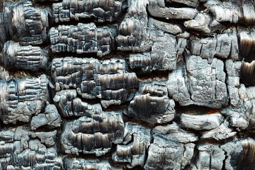 The charred wooden black wall after a fire