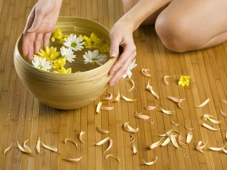 hands near a basin with flowers and water