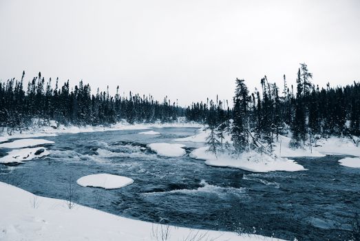 A winter landscape showing a foggy river in blue tones