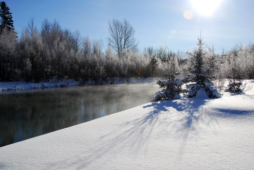 A winter landscape showing a foggy river on a cold day