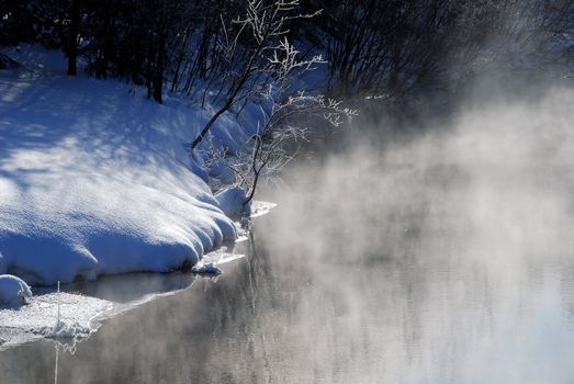 A winter landscape showing a foggy river on a cold day