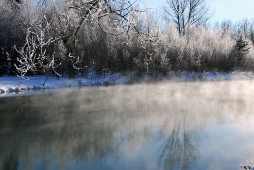 A winter landscape showing a foggy river on a cold day