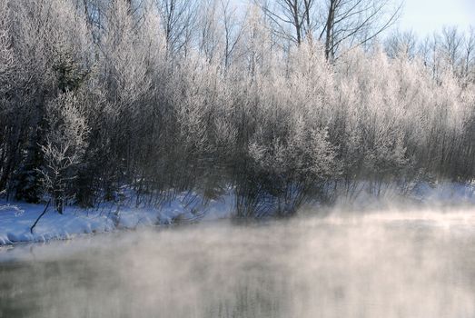 A winter landscape showing a foggy river on a cold day