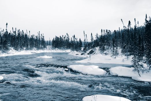 A winter landscape showing a foggy river in blue tones