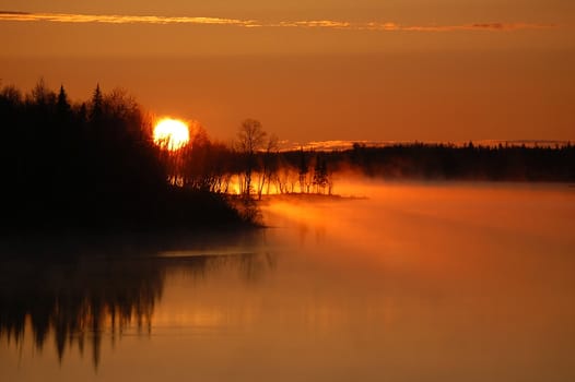 A colorful sunrise over a foggy Northern River