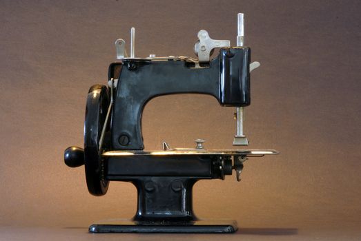 A vintage sewing machine against a brown background