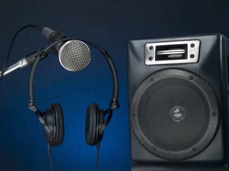 Professional microphone, headphone and speaker with a defused blue background.