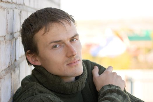 Portrait of the young man in a green sweater on an abstract background