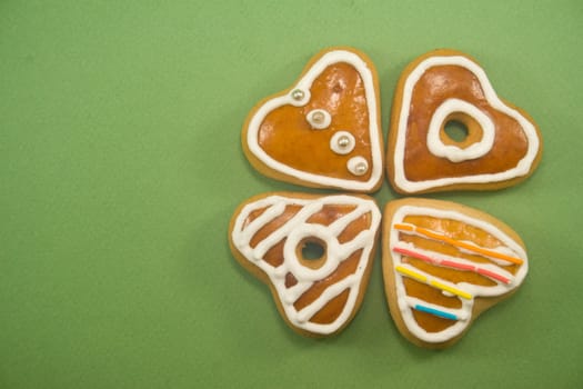 Decorated Christmas cookies in clover formation against green background ad space on left