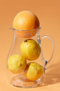 Orange and lemon in a glass jug on bright background