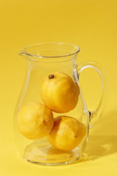 Lemons in a glass jug on bright background