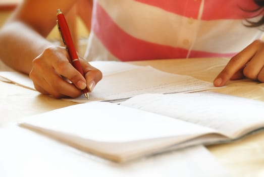 schoolgirl with pen writing down in notebook homework