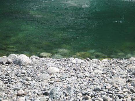grey polished rocks and green river water