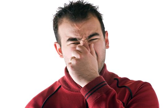 A young man holds or pinches his nose shut because of a stinky smell or odor.