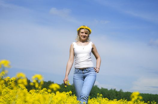 cute young blond woman outdoor in a yellow field wreath on head enjoy in nature