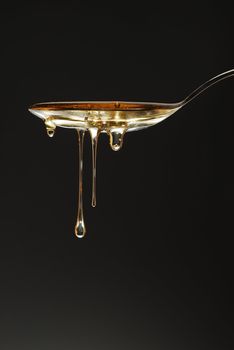Golden honey drops over the spoon stock photo