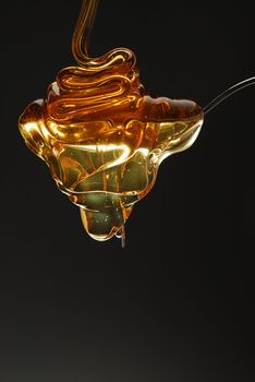 Golden honey spilling over the spoon stock photo