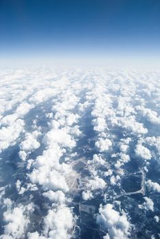 View at earth from airplane window at a high altitude above the clouds