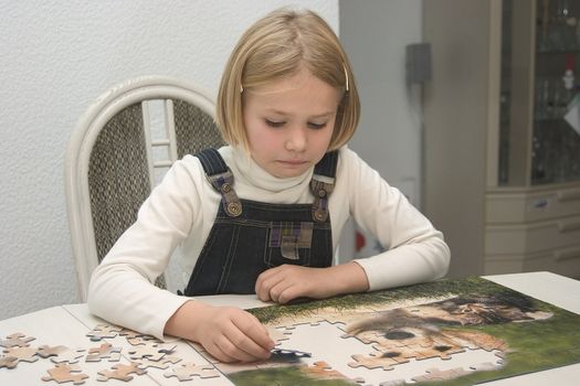 Child at the table arranges Jigsaws