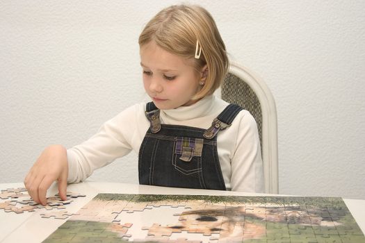 Child at the table arranges Jigsaws