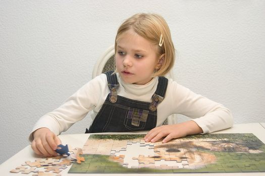 Child at the table arranges Jigsaws