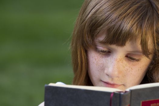 Young beautiful girl reading a book outdoor