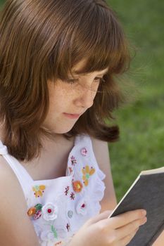 Young beautiful girl reading a book outdoor