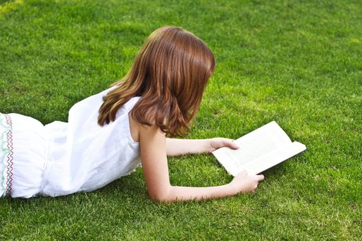 Young beautiful girl reading a book outdoor