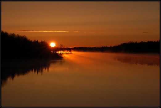 Bright and orange sunrise over a northern river