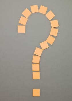 Question Mark made of Orange Adhesive Notes on grey background
