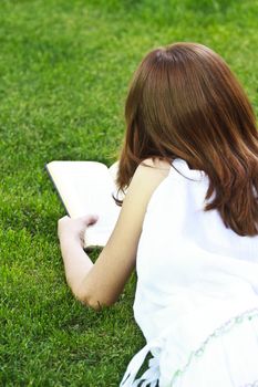 Young beautiful girl reading a book outdoor