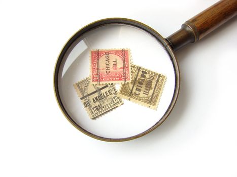 US postage stamps and magnifying glass on white background