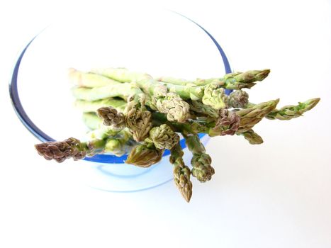 Bunch of asparagus in a bowl ready to cook, on white background