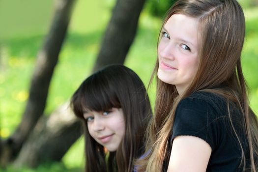 Two beauty teenage girls portrait on background with green forest