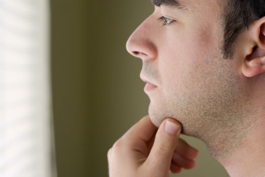 A young man with his hand on his chin thinking an important decision.