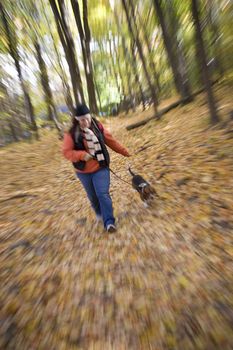 A young woman walking her dog through the woods with a zoom blur effect.