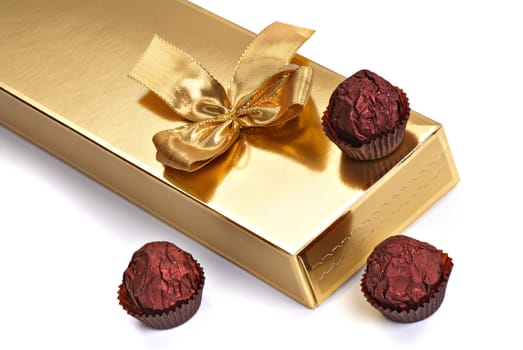 A gold boxed gift with gold ribbon and sweet.